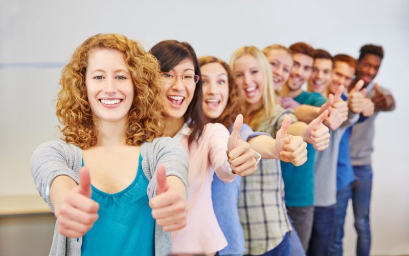 Viele Teenager hintereinander halten ihre Daumen hoch zum Gratulieren