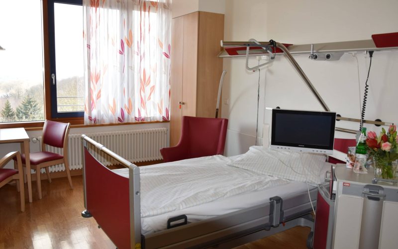 Ein unbelegtes Krankenhausbett mit Fenster im Hintergrund