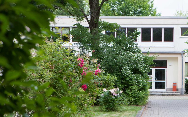 Wohnheimeingang mit grünen Büschen davor