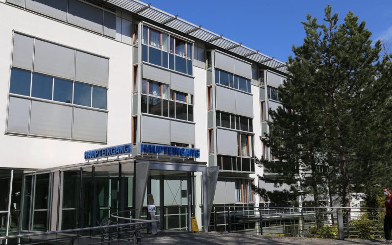 Ein Gebäude mit gläsernem Eingangsbereich, über dem "Haupteingang" steht